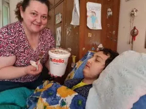 Giuseppina porge barattolone Nutella a Eugenio nel lettuccio