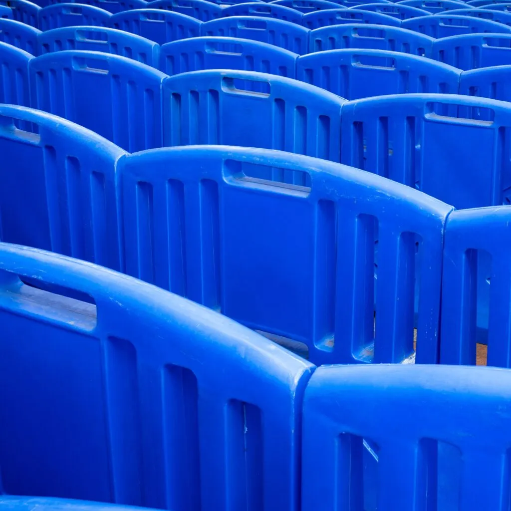 A pattern of blue plastic chairs stacked closely together, creating an abstract visual.