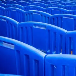 A pattern of blue plastic chairs stacked closely together, creating an abstract visual.