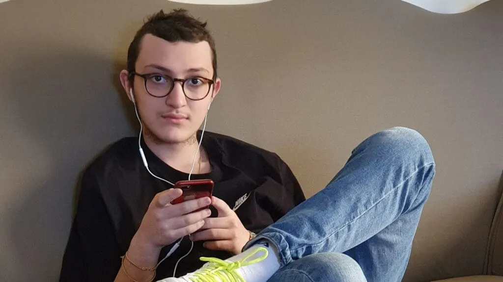 primo piano Eugenio sul divano con le cuffiette e scarpette bianche