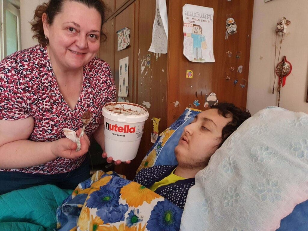 Giuseppina porge barattolone Nutella a Eugenio nel lettuccio