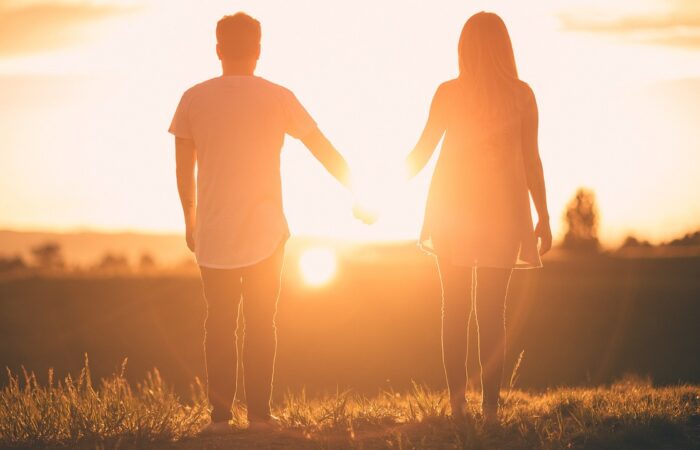 uomo e donna mano nella mano al tramonto