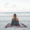 woman sitting on blanket located on shoreline