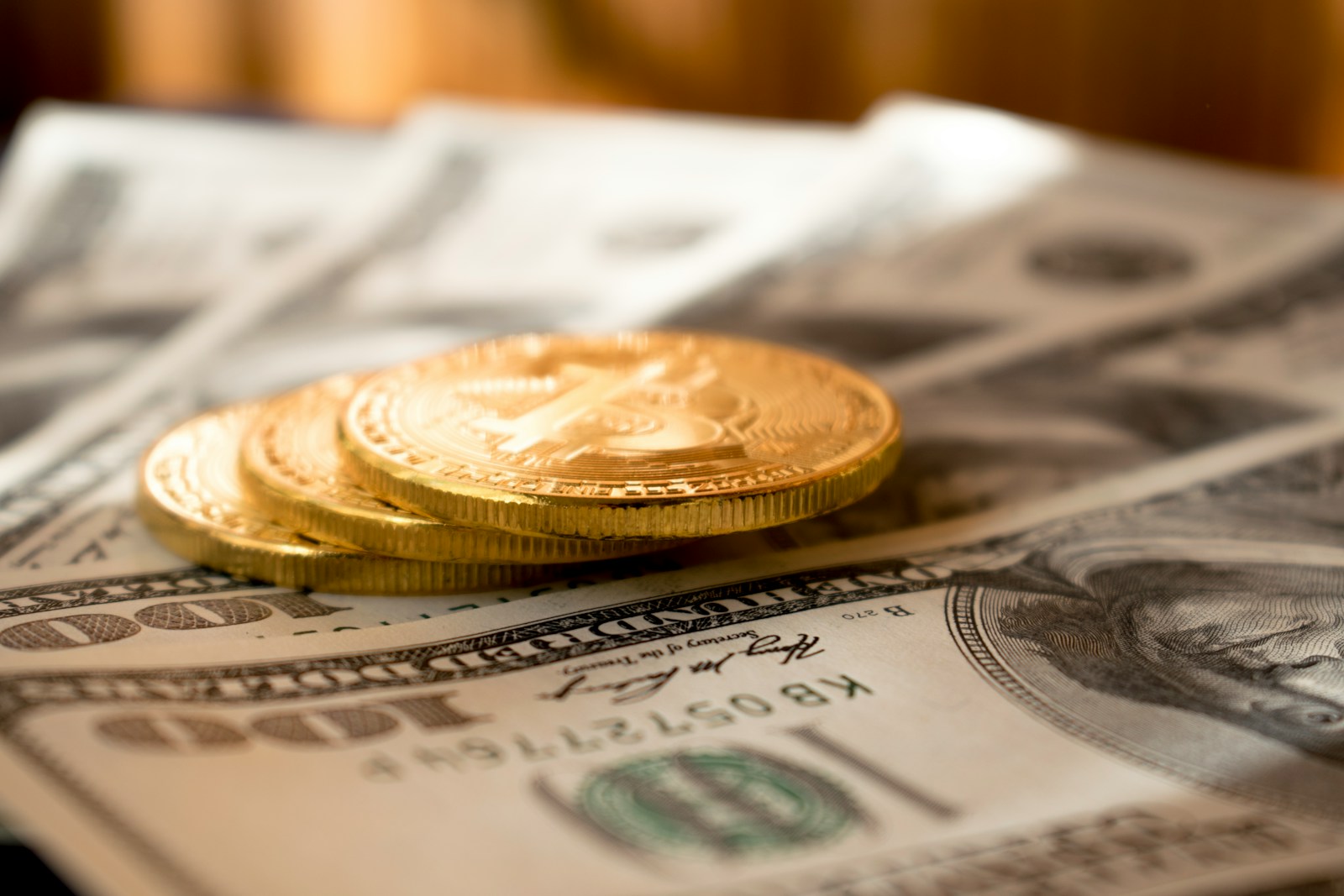 Photo by Dmytro Demidko three round gold-colored coins on 100 US dollar banknotes