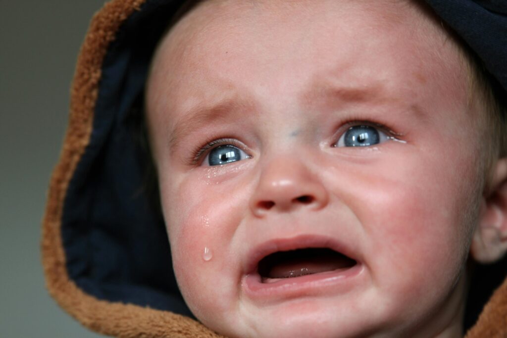 Emotional close-up of a baby in tears, highlighting raw emotion and vulnerability.