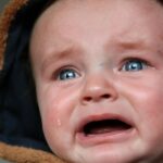 Emotional close-up of a baby in tears, highlighting raw emotion and vulnerability.